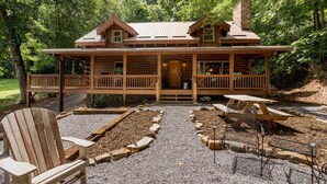 Une cabane en bois avec un porche, un espace pique-nique couvert et une allée gravillonnée.