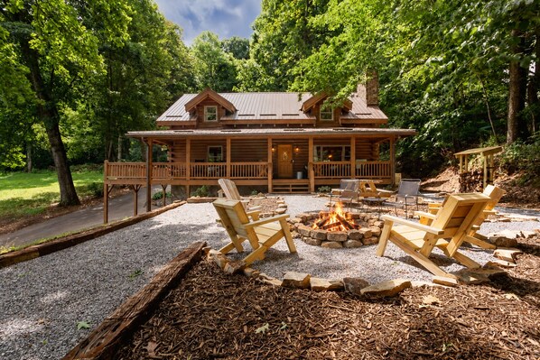 A log cabin with a deck, outdoor seating, and a fire pit.