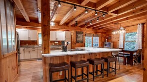 L’intérieur d’un chalet rustique est agrémenté d’un bar en bois, de meubles blancs et d’une grande fenêtre.