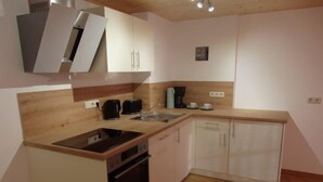 A compact kitchen with a sink, stove, and cabinets. - Ferienwohnung Jenner 48 qm, für 2 Personen, Balkon, 1 Schlafzimmer (Schönau am Königssee)