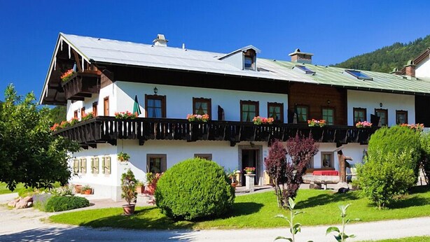 A traditional Alpine-style building with a balcony, potted plants, and a well-maintained lawn. - Ferienwohnung Jenner 48 qm, für 2 Personen, Balkon, 1 Schlafzimmer (Schönau am Königssee)