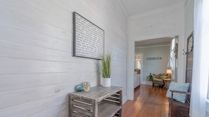 A hallway with a wooden bench, a potted plant, and a sign reading "BEACH HOUSE". - Walk to Beach & UTMB |Dogs Ok |Game Room (Galveston)