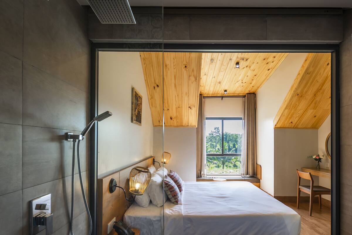 Une chambre moderne avec un grand lit, un plafond en bois et une vue sur l’extérieur.