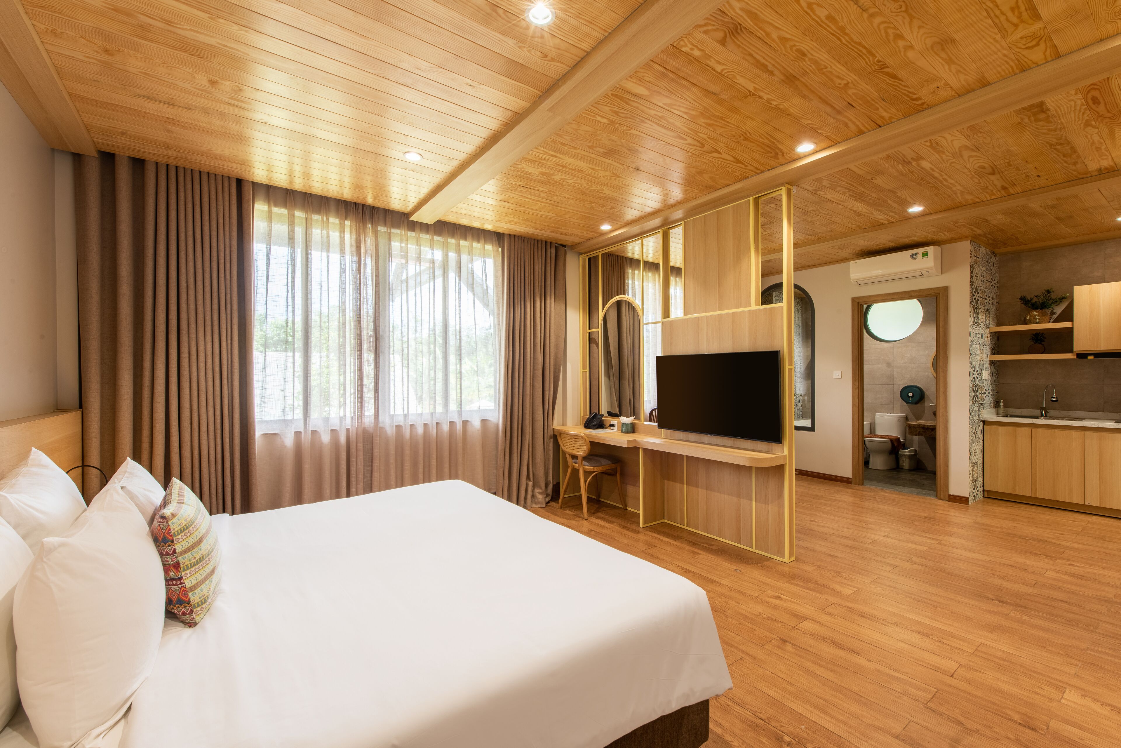Una habitación de hotel moderna con una cama grande, un escritorio, un televisor y una kitchenette.