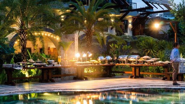 A poolside dining area with tables, chairs, and a pool reflecting lights. - Hami Garden (Tan An)
