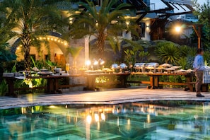 A poolside dining area with tables, chairs, and a pool reflecting lights. - Hami Garden (Tan An)