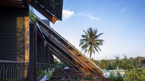 A modern building with a sloped roof and a staircase leading to a balcony. - Hami Garden (Tan An)