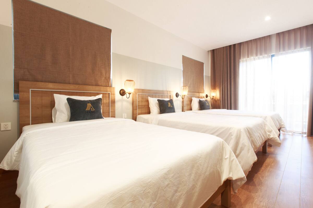 Une chambre d’hôtel avec deux lits, des têtes de lit en bois et des lampes fixées au mur.