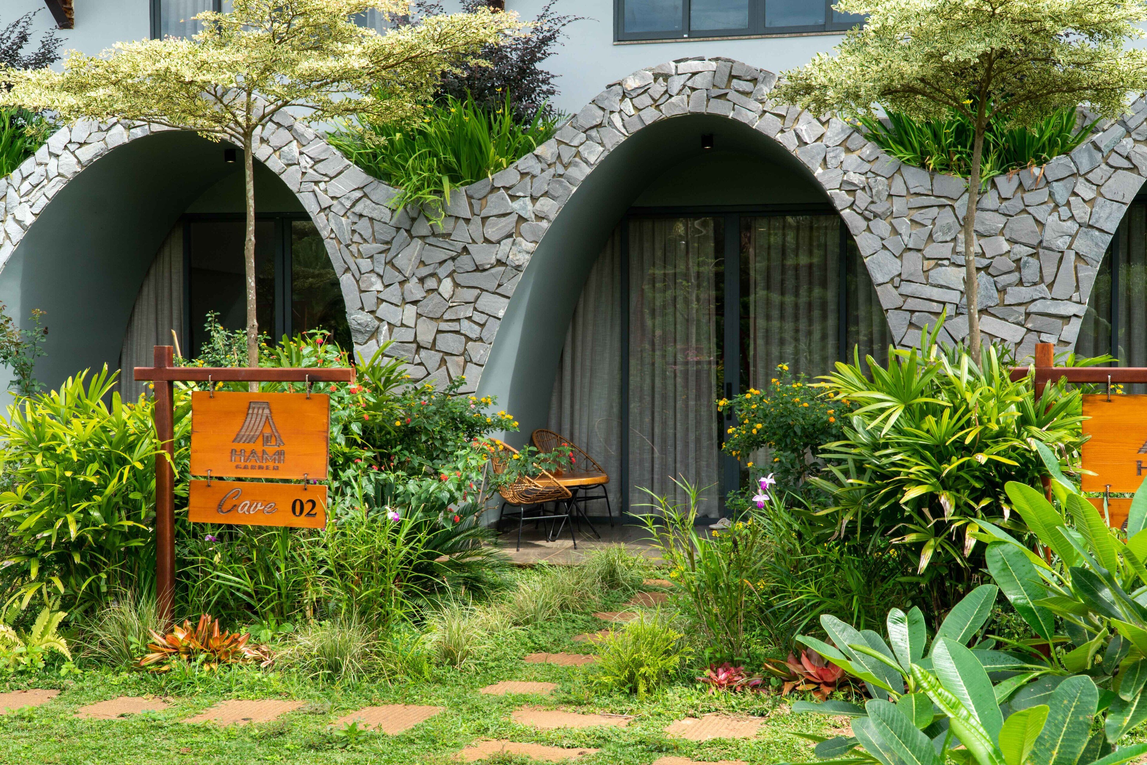 Un jardín con un arco de piedra, un banco de madera y un cartel que indica una cueva.