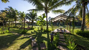 A tropical garden with palm trees, a wooden gazebo, and a stone pathway. - Hami Garden (Tan An)
