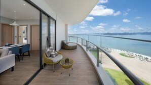 Ein Balkon mit Blick auf den Strand, eine Essecke mit Tisch und Stühlen sowie Korbmöbel.