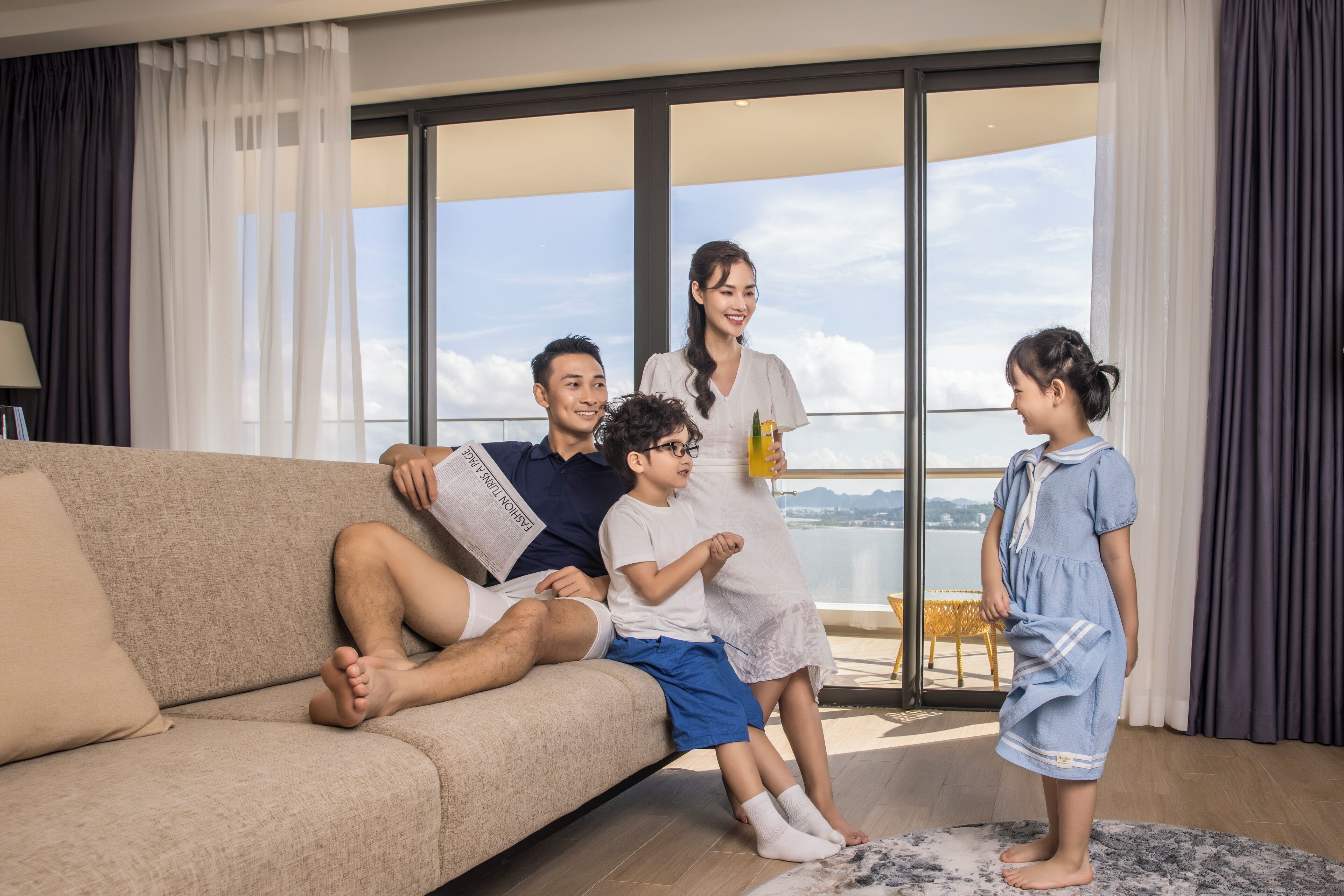 A family of four on a sofa with a large window behind them.