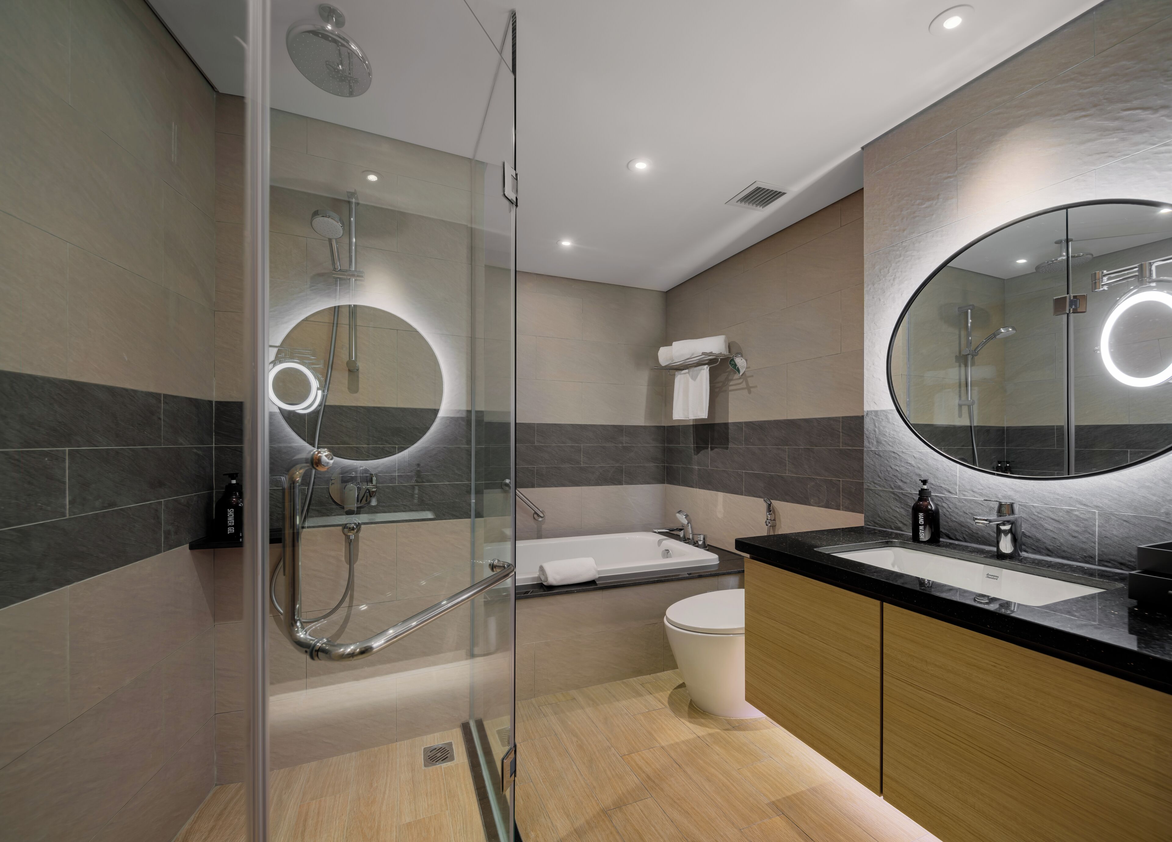 A modern bathroom with a glass-enclosed shower, a freestanding bathtub, and a vanity with a large mirror.