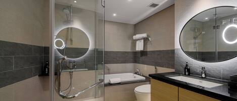 A modern bathroom with a glass-enclosed shower, a freestanding bathtub, and a vanity with a large mirror.
