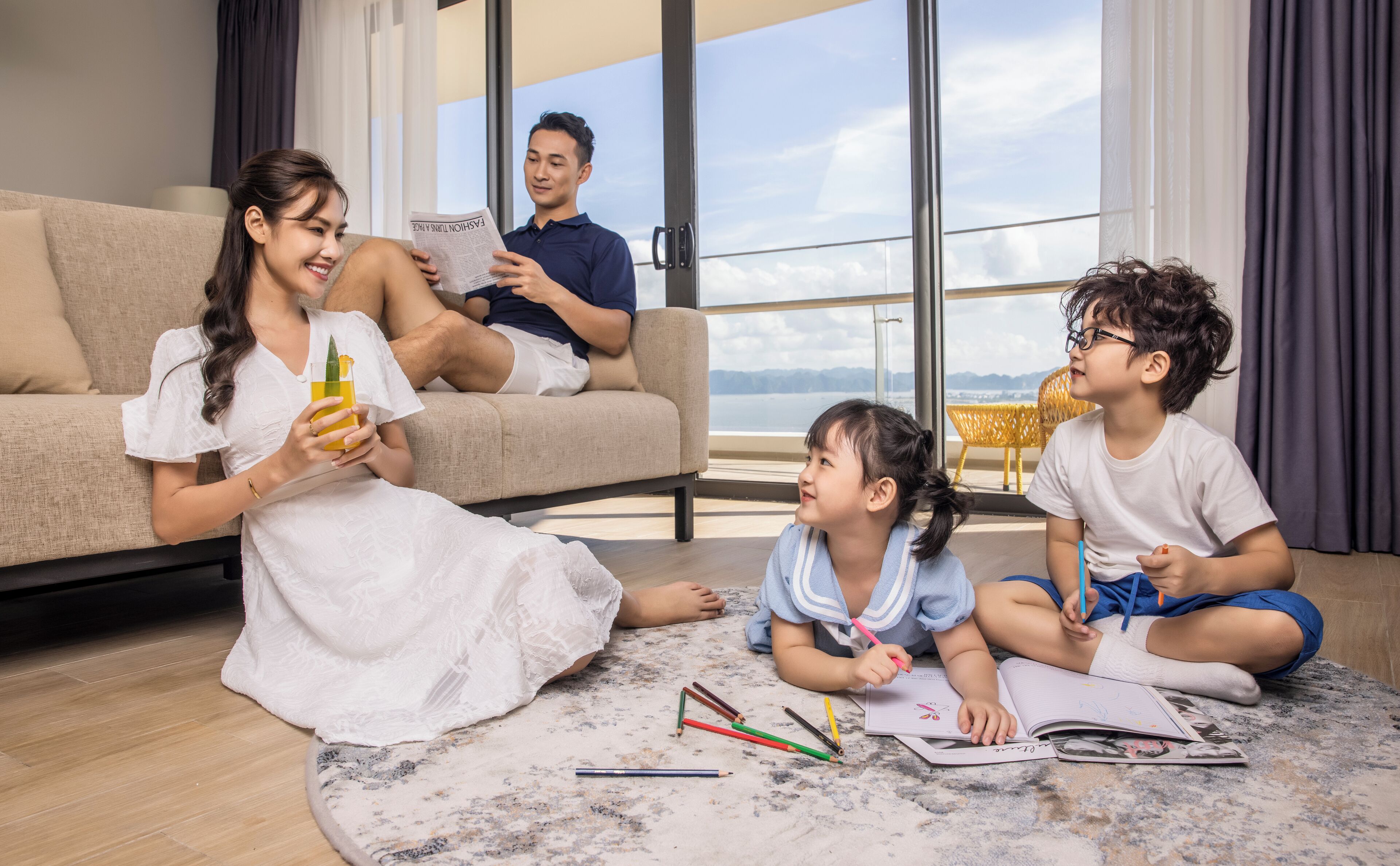 A family in a modern living room with a large window overlooking a scenic view.