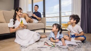 A family in a modern living room with a large window overlooking a scenic view.