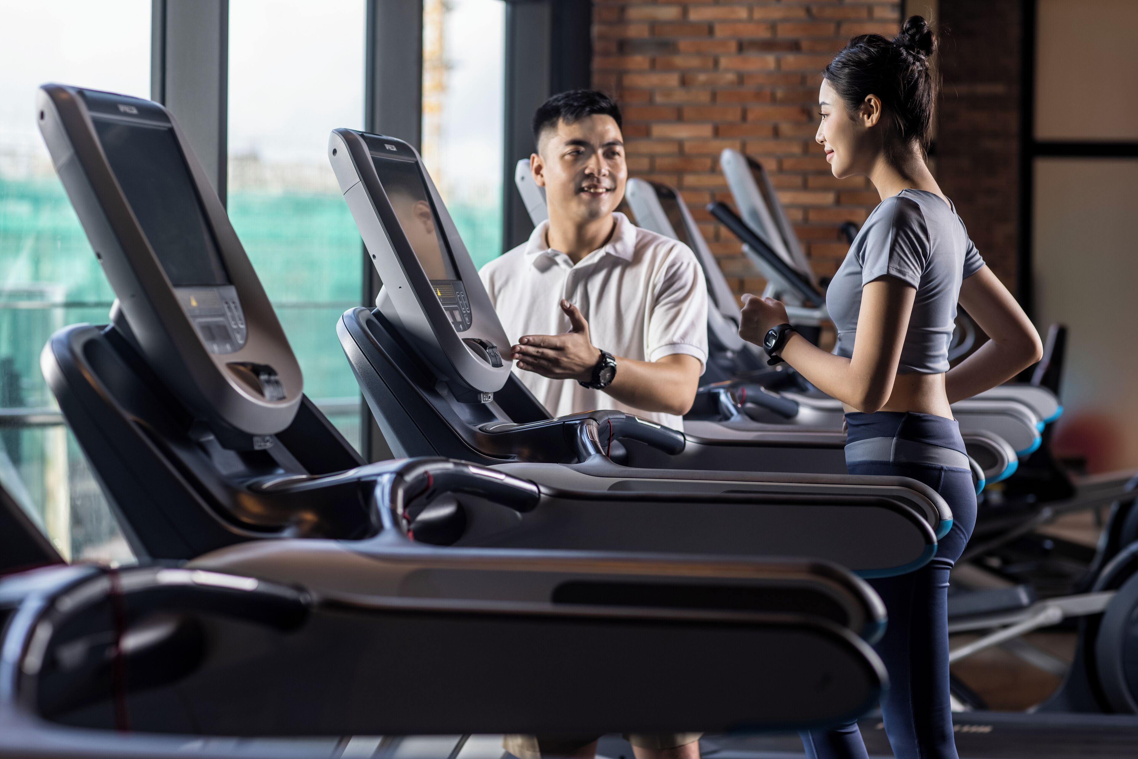 Ein Fitnessstudio mit Laufbändern und einer Person, die eines benutzt.