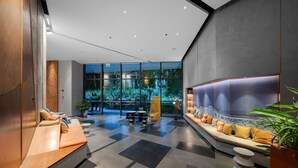 Eine moderne Lobby mit Sitzgelegenheiten, einem Empfangsbereich und einem großen Fenster mit Blick auf Grünflächen.