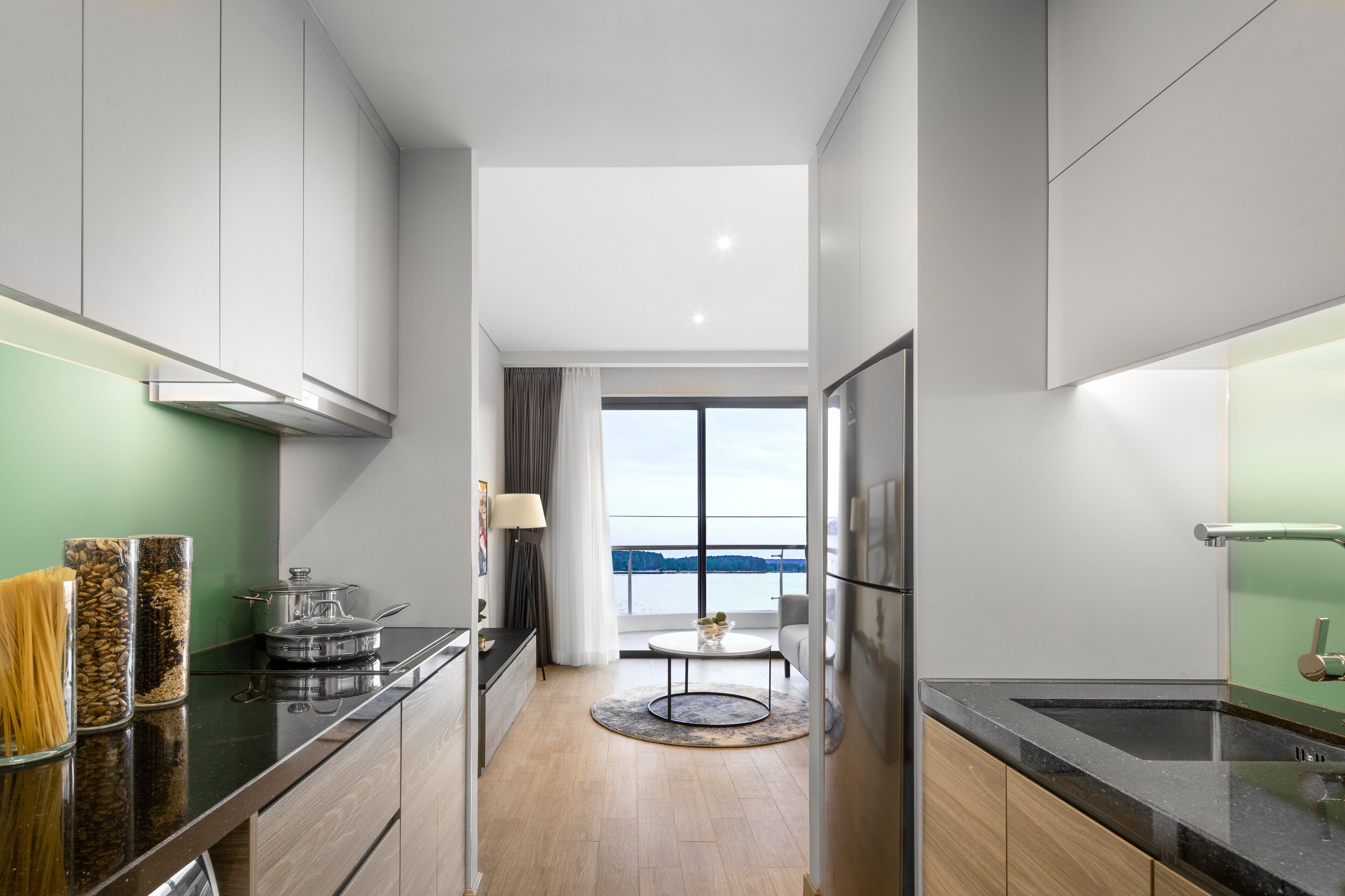 A modern kitchen with a view of the sea, a round dining table, and a large window.