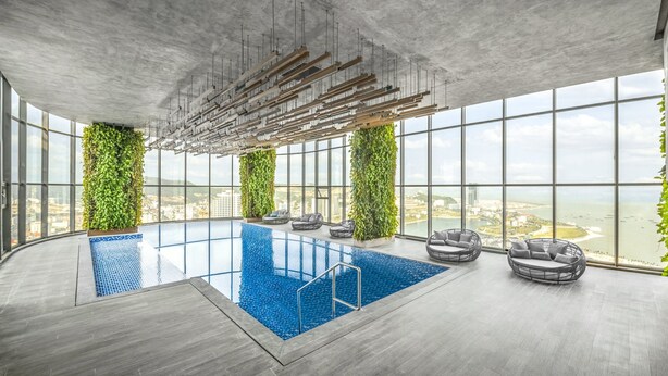 Ein moderner Innenpool mit Blick auf die Stadt, großen Fenstern und Grünpflanzen.