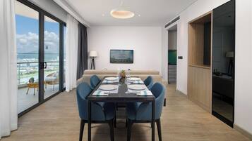 A dining area with a table set for four, a sofa, and a view of a cityscape through large windows.