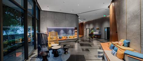 A modern lobby with a seating area, a reception desk, and a view of the outdoors.