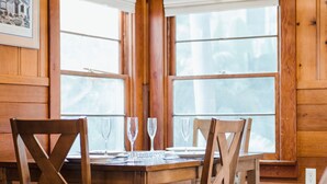 Comedor de madera con una mesa dispuesta para cuatro personas, dos sillas a cada lado y una araña colgante.