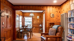 Un interior de madera con una zona de comedor, un sofá de cuero y una estantería.