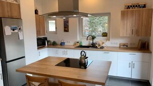 A modern kitchen with a central island, wooden cabinets, and a window providing natural light. - New Spacious Appart. Incredible view of Mt Blanc (Passy)