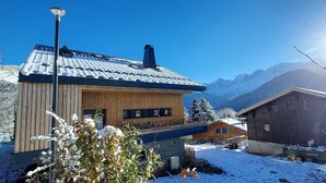 A wooden cabin with a sloped roof, a balcony, and a view of snow-covered mountains. - New Spacious Appart. Incredible view of Mt Blanc (Passy)