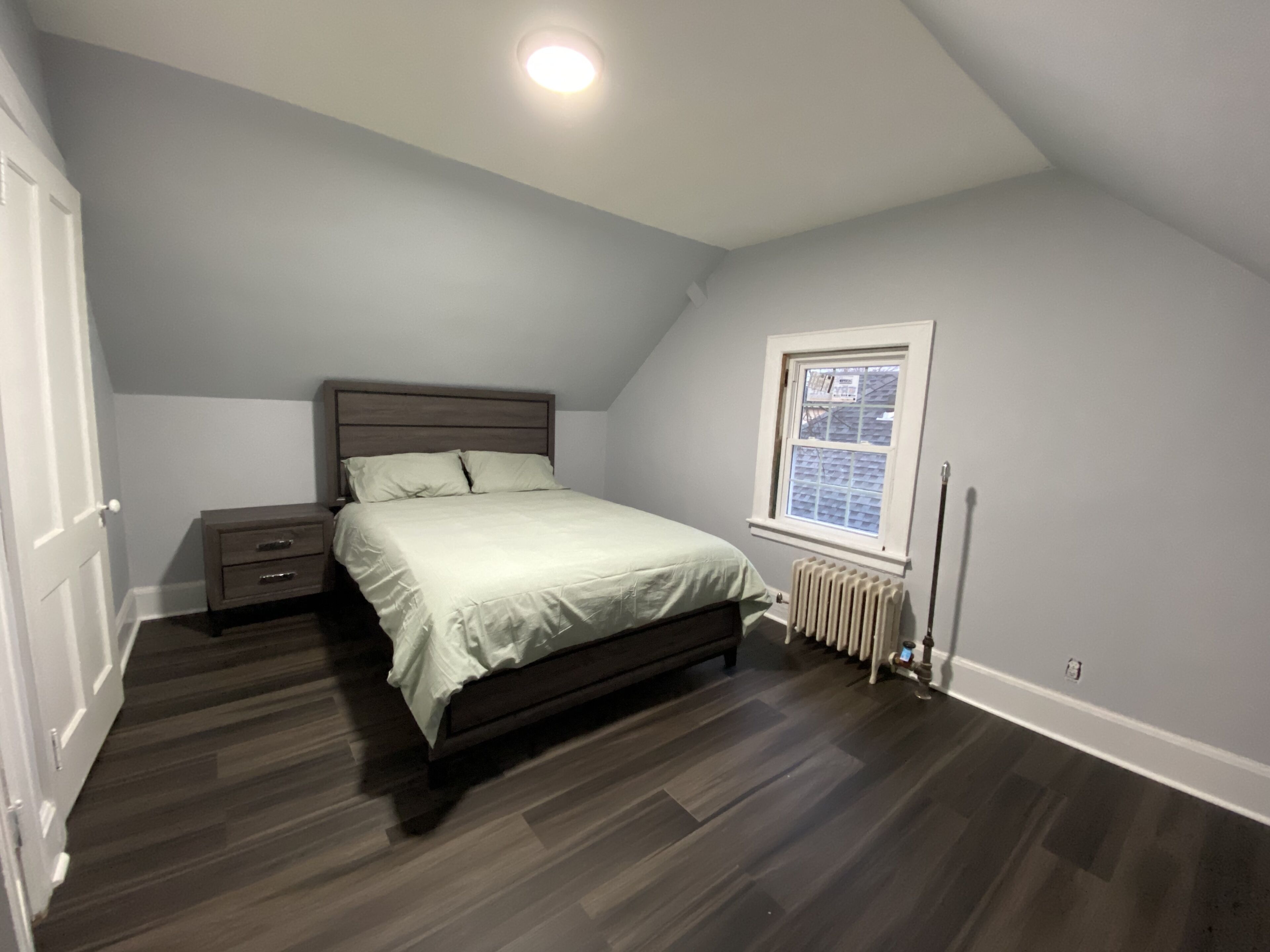 A bedroom with a bed, nightstand, dresser, and a window with blinds.