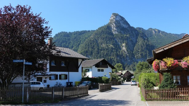A street view with houses, a mountain in the background, and a clear sky. - Relaxation in the Ammergau mountains, centrally located (Oberammergau)