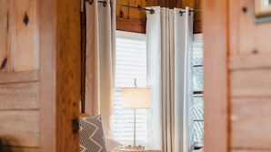 Ett rum med träpanel, en säng, gardiner, en lampa och en takfläkt.
