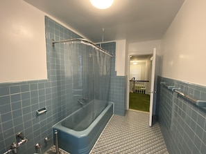 Een bad/douchecombinatie, handdoeken, zeep, shampoo