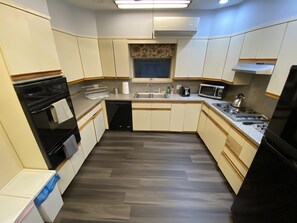 A compact kitchen with a dishwasher, oven, microwave, and a small window above the sink.
