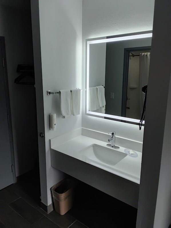 A bathroom with a white sink, a mirror with a light, and two towels on towel hooks. - Quality Inn (New Martinsville)
