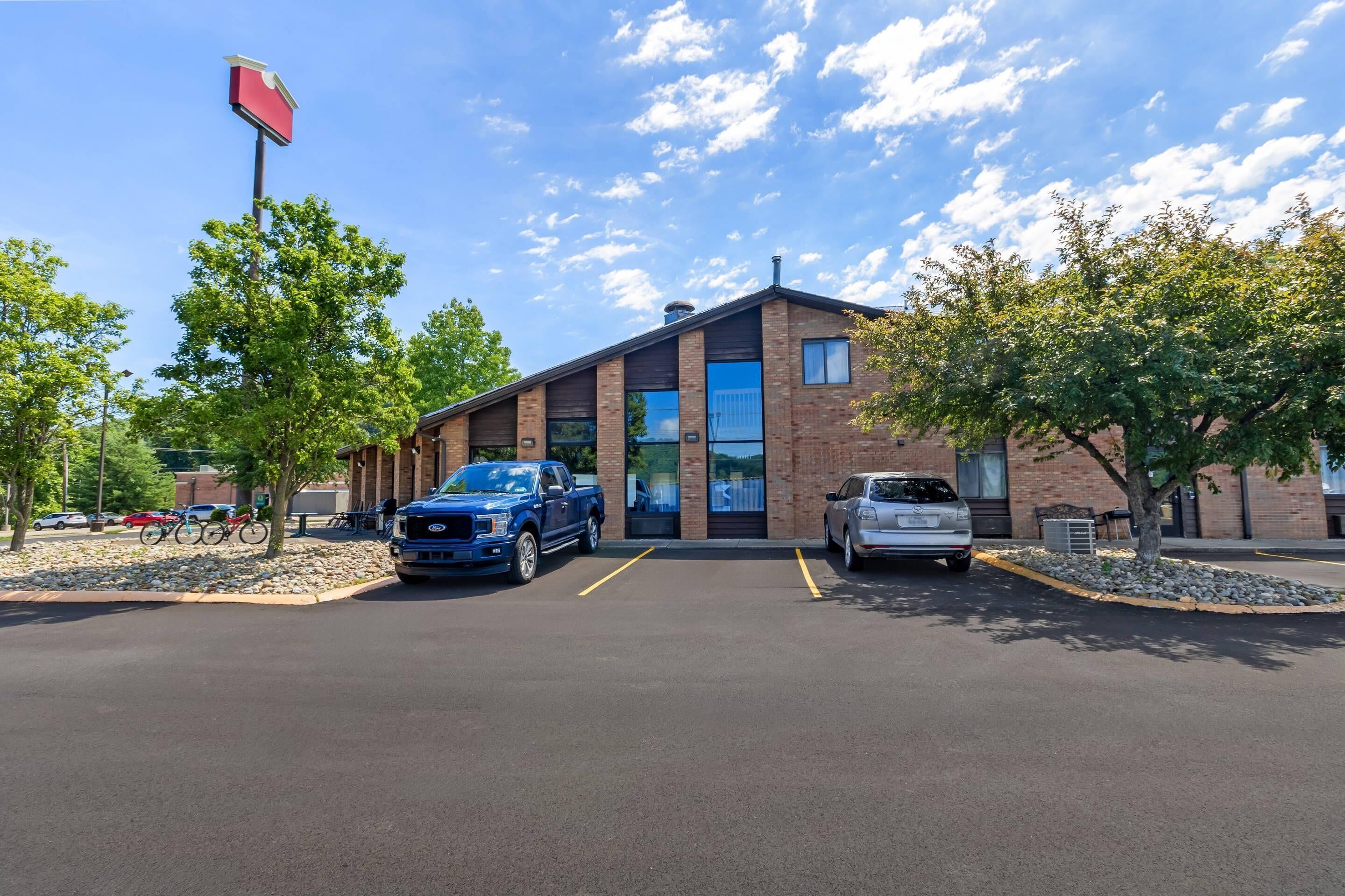 A building with a brick facade, a blue truck, and a silver car parked in front.