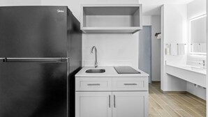 A compact kitchen with a black refrigerator, a sink, and a countertop. - Quality Inn (New Martinsville)
