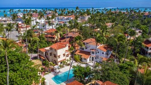 A coastal residential area with multiple houses, a swimming pool, and palm trees. - Amazing Villa Bavaro Beach (Punta Cana)