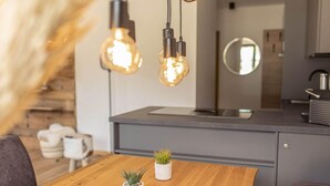 Una cucina moderna con un tavolo da pranzo in legno, due piante in vaso e lampade a sospensione.