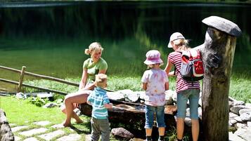 A group of people near a lake with a wooden structure and a stone path.