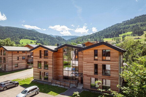 Ein modernes Holzgebäude mit mehreren Stockwerken, großen Fenstern und einem Parkplatz.