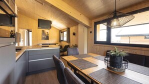 Una cucina moderna con pareti in legno, una zona pranzo con tavolo e sedie in legno, e un'ampia finestra che fa entrare luce naturale.