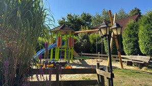A playground with a colorful play structure, swings, and a slide. - Holiday apartment in the Naturpur holiday village (Brakel-Bellersen)