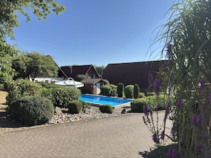 A swimming pool surrounded by well-maintained bushes and a clear blue sky.