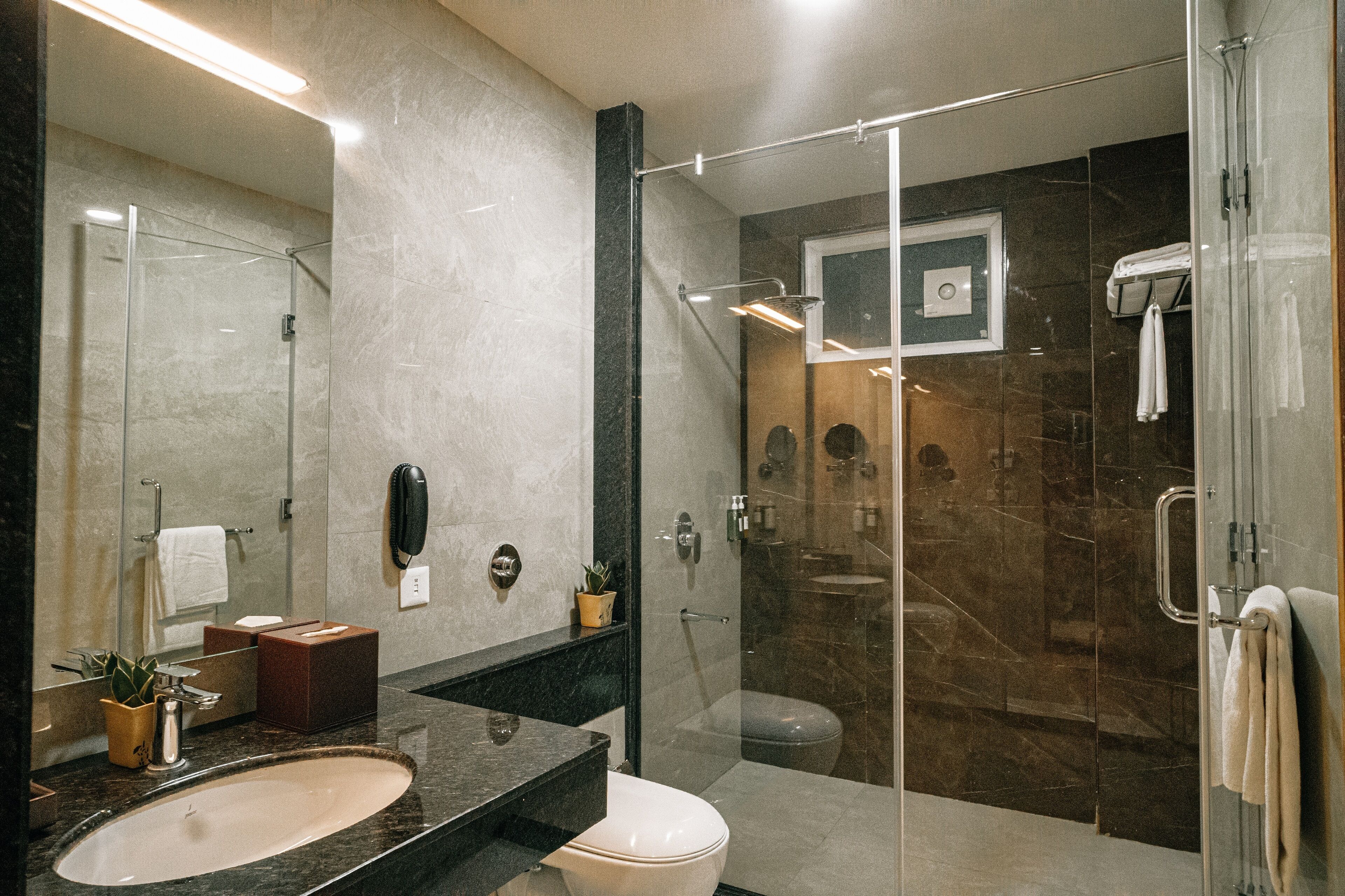 Une salle de bain moderne avec une douche à parois de verre, un lavabo en marbre et un grand miroir.