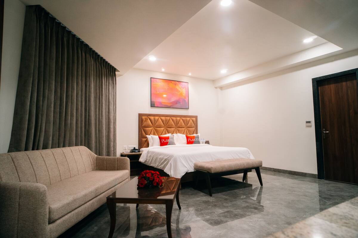 Ein Hotelzimmer mit Bett, einer Sitzecke, einer Bank, einem Couchtisch und einem Bild an der Wand.