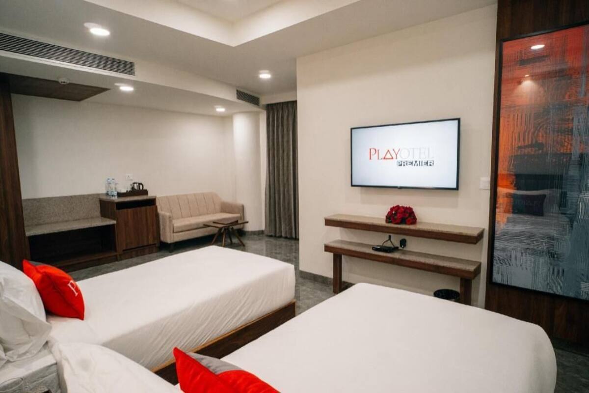 Ein Hotelzimmer mit zwei Betten, einem Fernseher, einem Sofa und einem Schreibtisch.