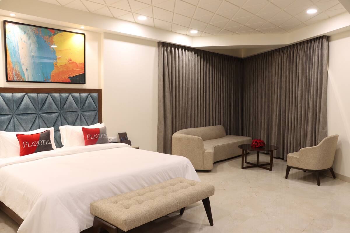 Ein Hotelzimmer mit einem großen Bett, einer Couch, einem Sessel, einem kleinen Tisch und einem Gemälde an der Wand.
