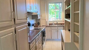 A kitchen with white cabinets, a stove, and a window providing natural light.